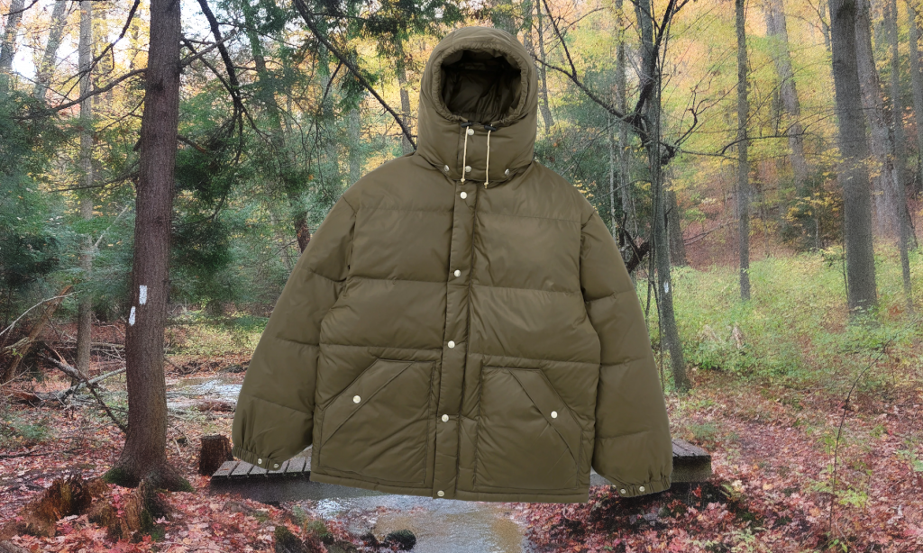 A military green hooded puffer coat with large pockets and brass buttons in a forest setting.