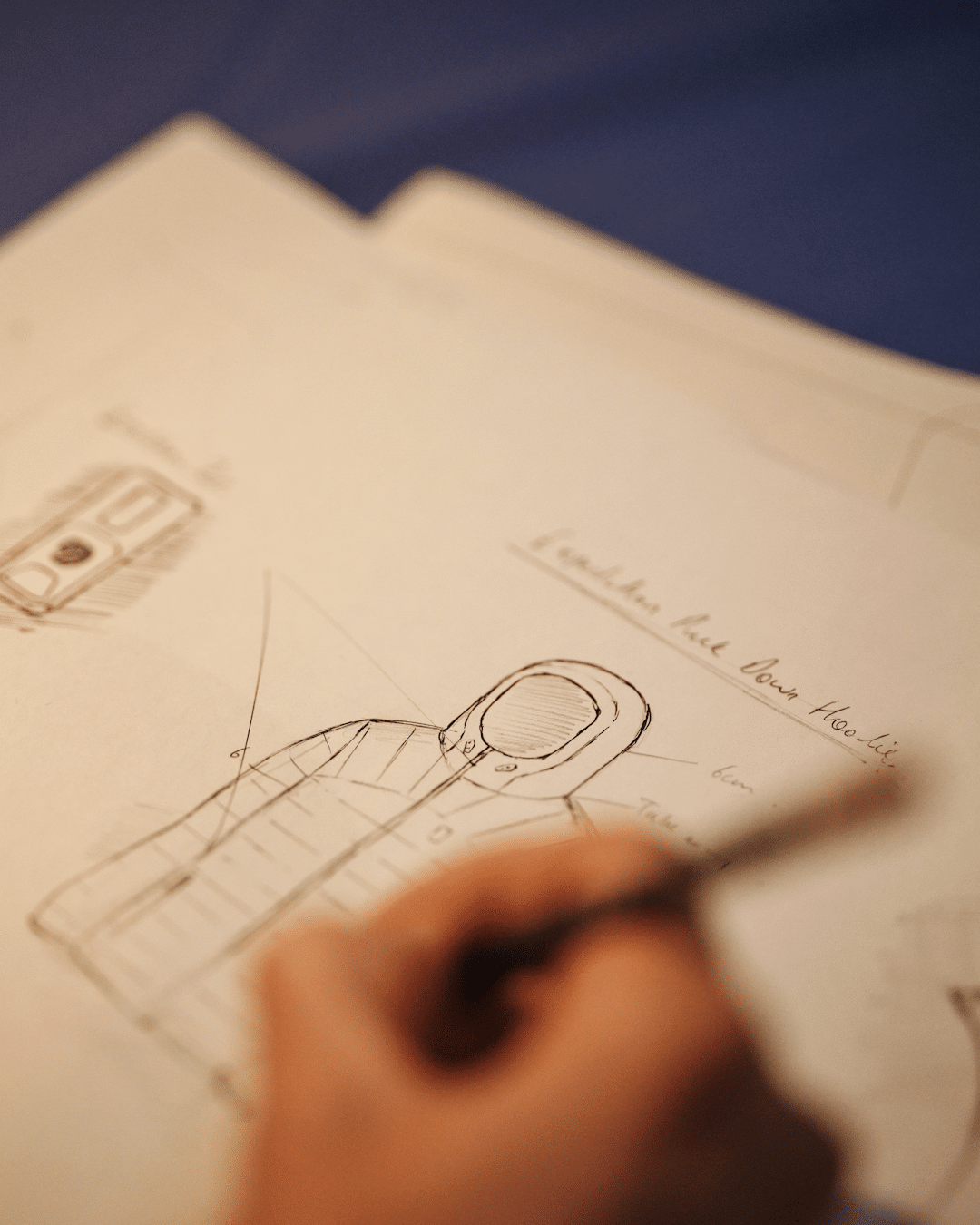 Technical sketches of a hooded garment with detailed design annotations.