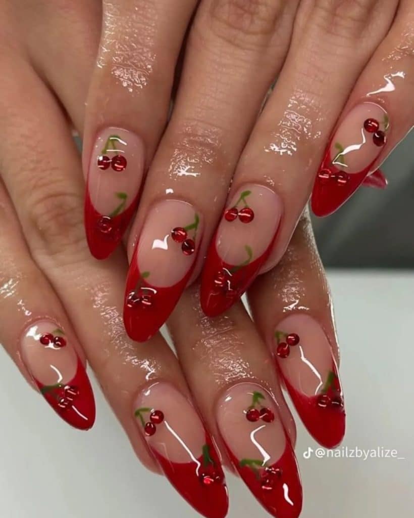 Glossy almond nails featuring raised red cherry charms and vibrant green stems.