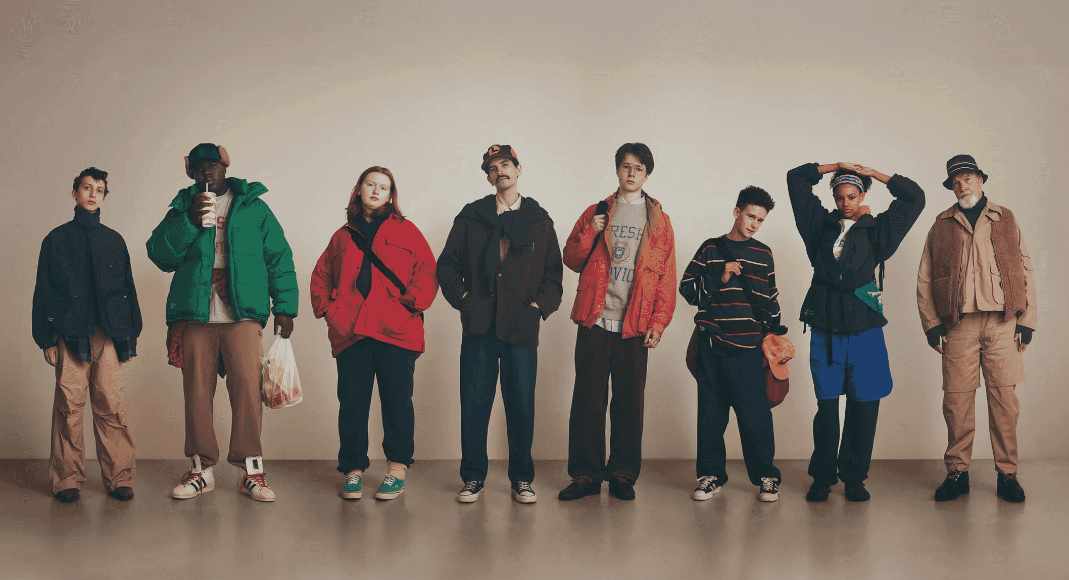 Group of models in retro-inspired techwear and puffer jackets posing against a neutral studio background.