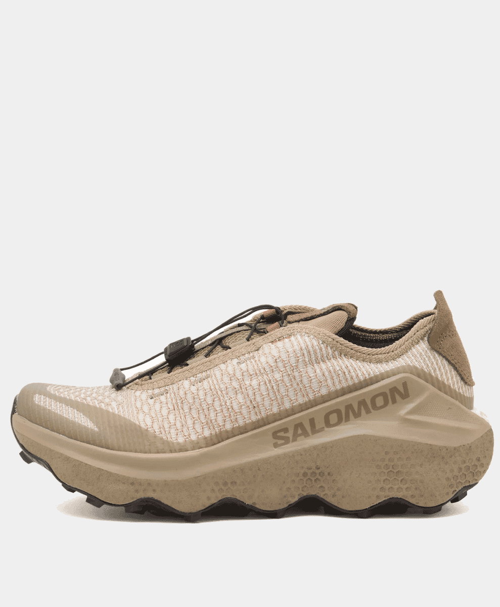 Beige Salomon trail running shoe with a textured knit upper and technical chunky midsole against a white background.