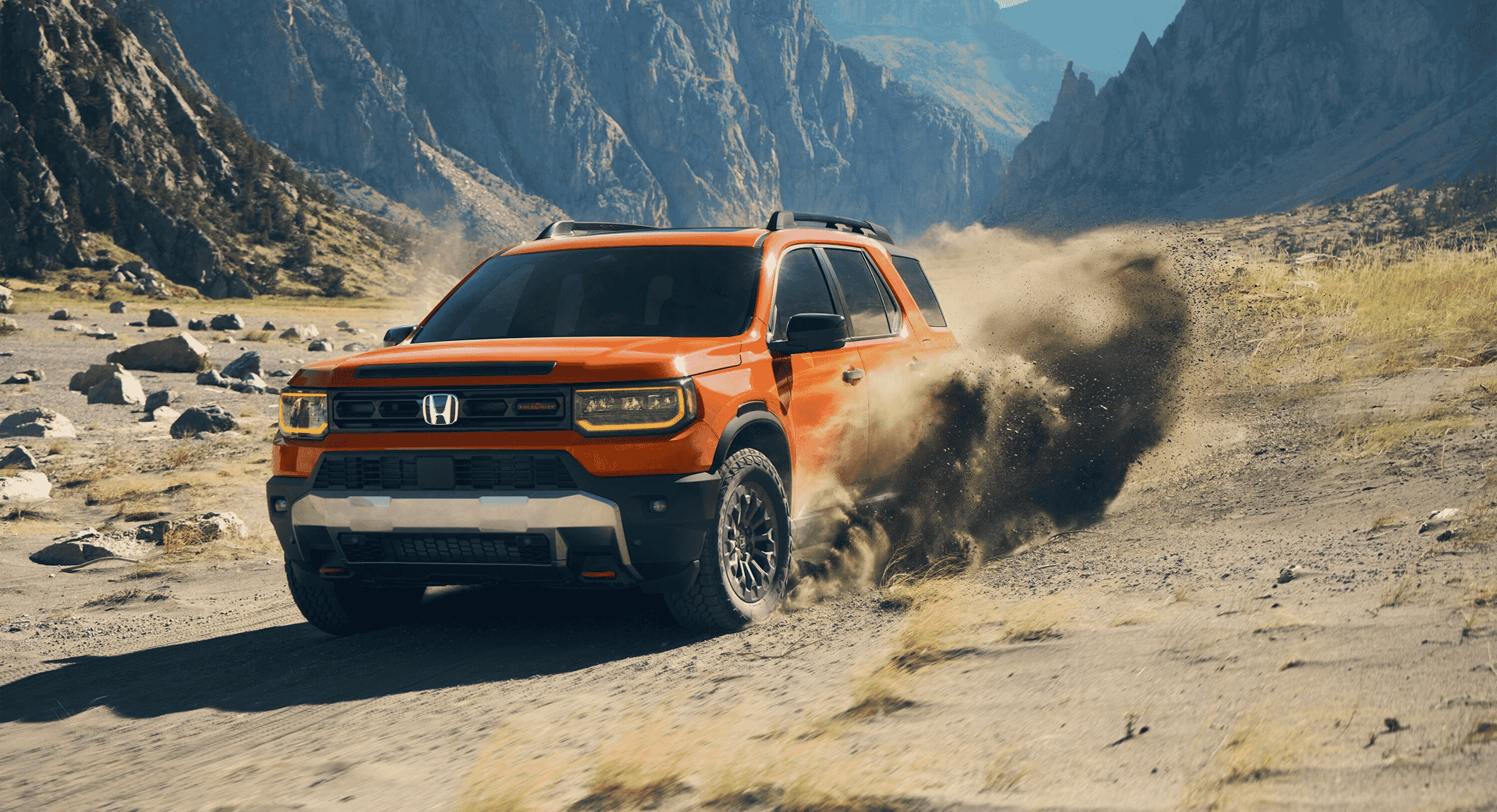 An orange Honda SUV kicking up dust on a rugged mountain trail in a desert landscape.