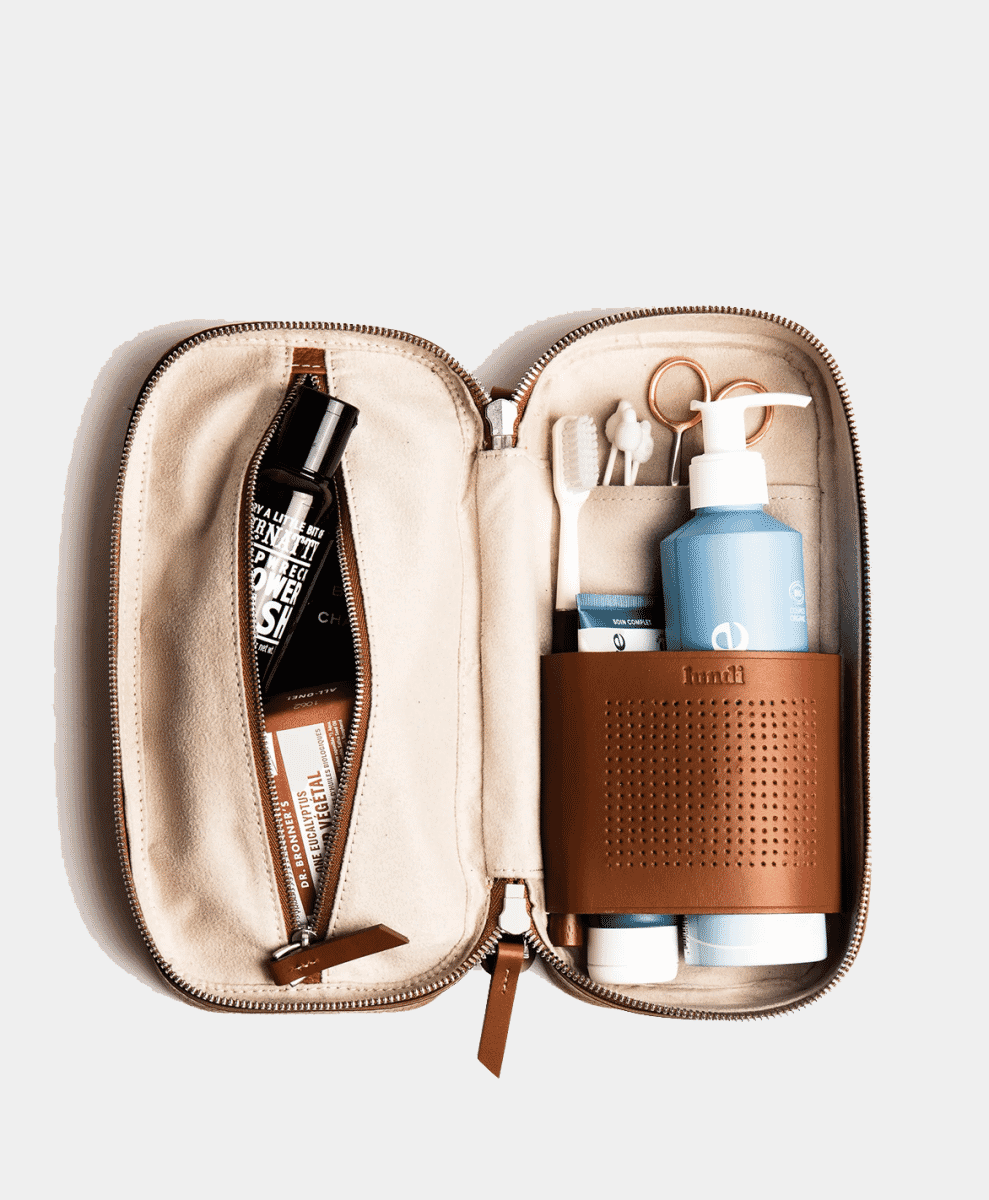 Open beige leather travel kit containing grooming essentials neatly arranged.