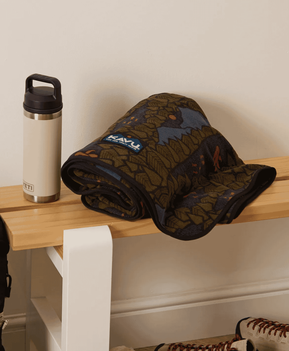 KAVU forest-patterned blanket resting on a wooden bench.