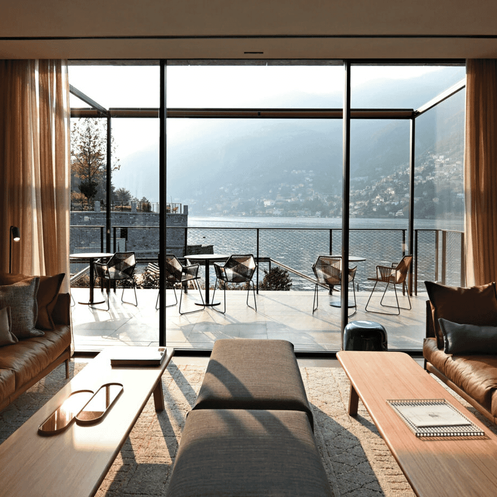 Minimalist living room with leather sofas and large windows overlooking the mountains and lake.