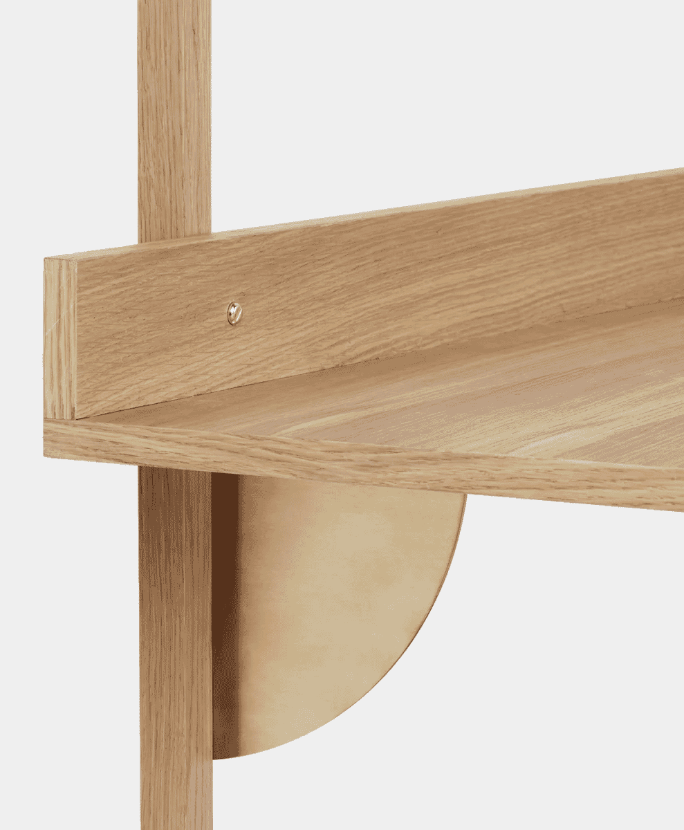 Detail shot of oak wood shelves supported by minimalist brass hardware.