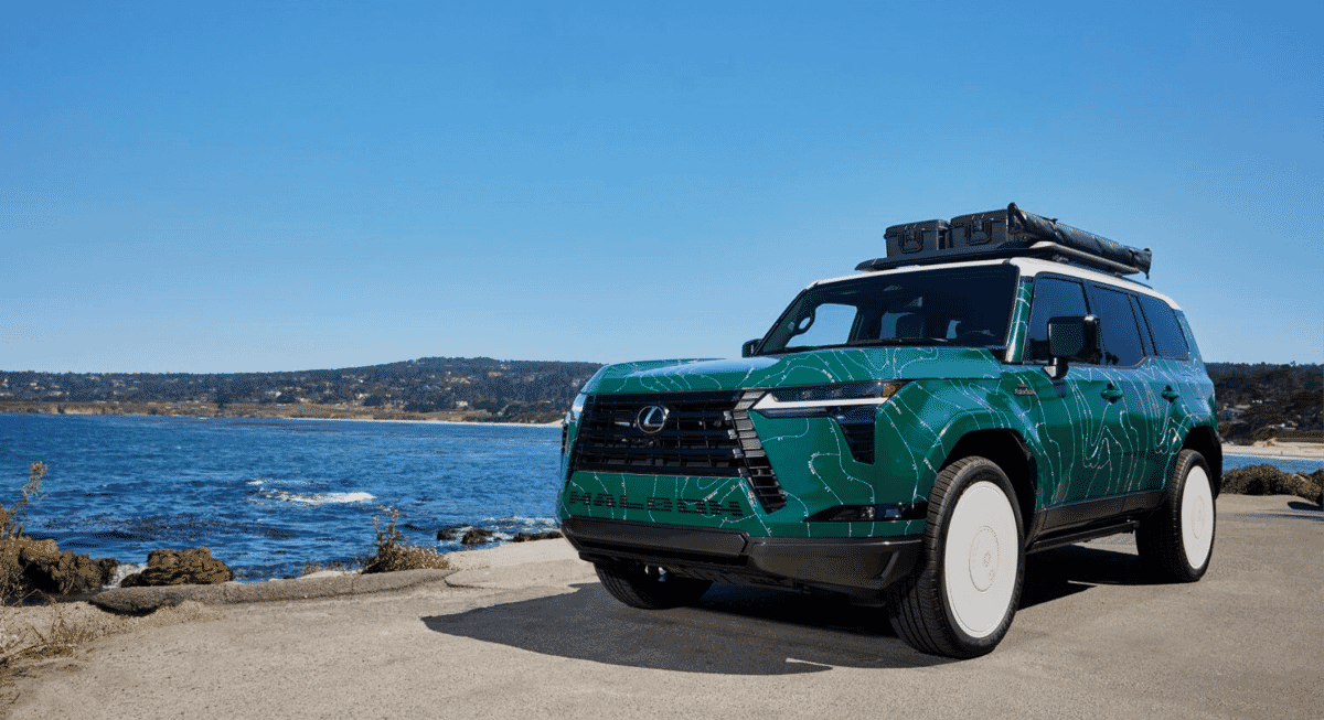 Side profile of a green Lexus SUV featuring white-walled tires and rooftop storage gear.