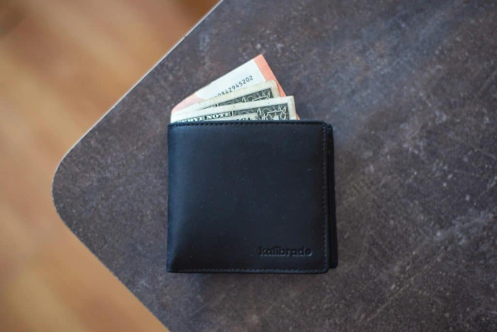 Detailed close-up of a black 'kalibrade' branded wallet showing leather texture.