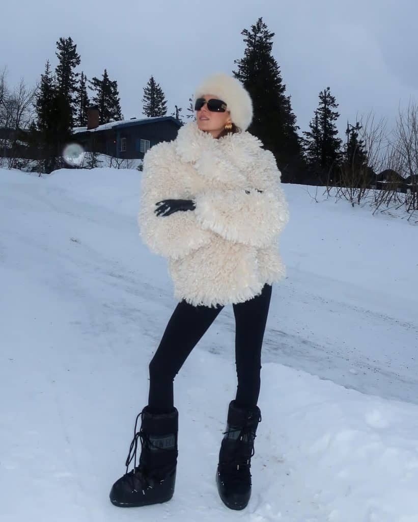 Woman in a voluminous white faux-fur coat and chunky snow boots.