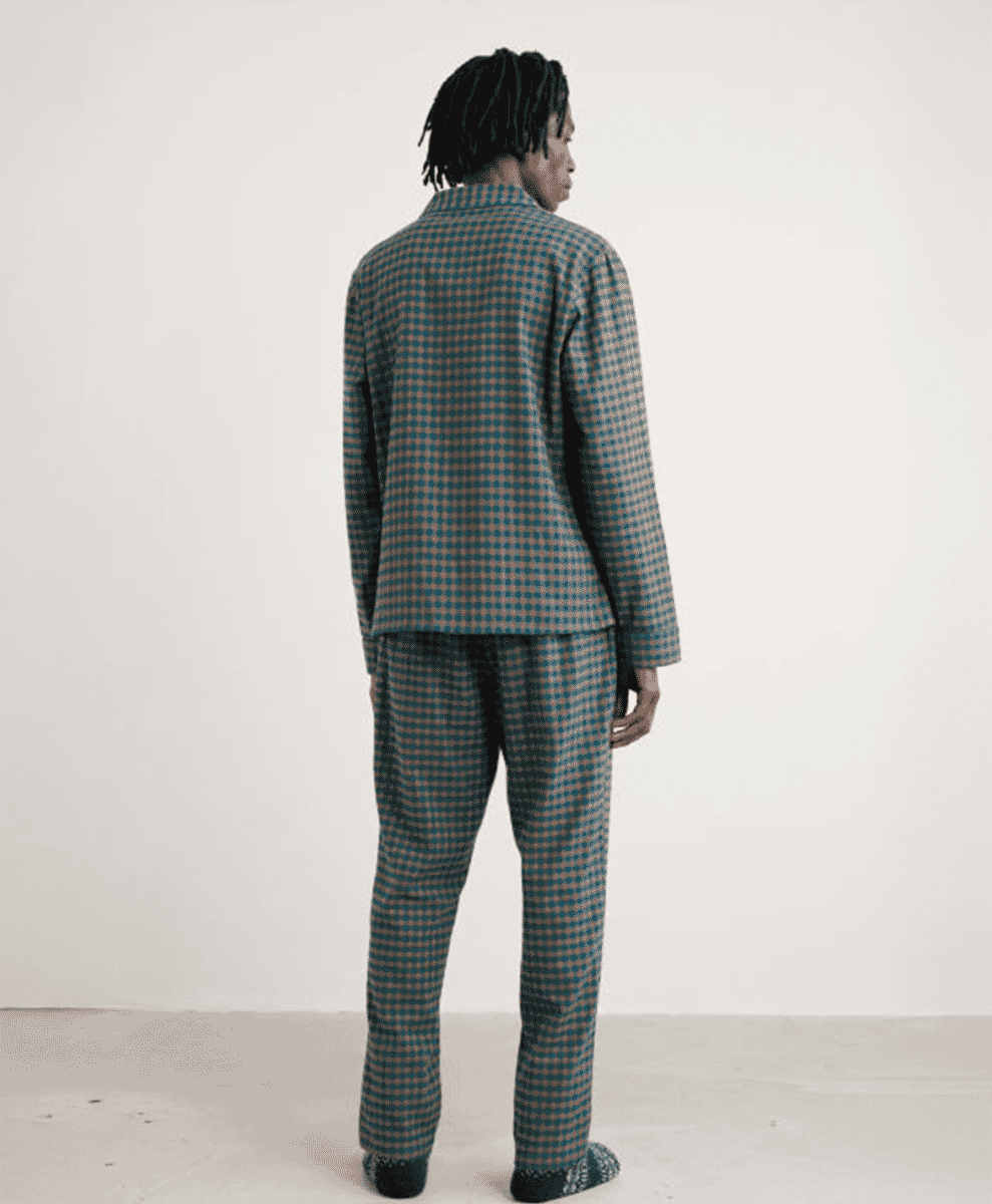 Rear view of a man wearing a teal and brown houndstooth flannel pajama set.