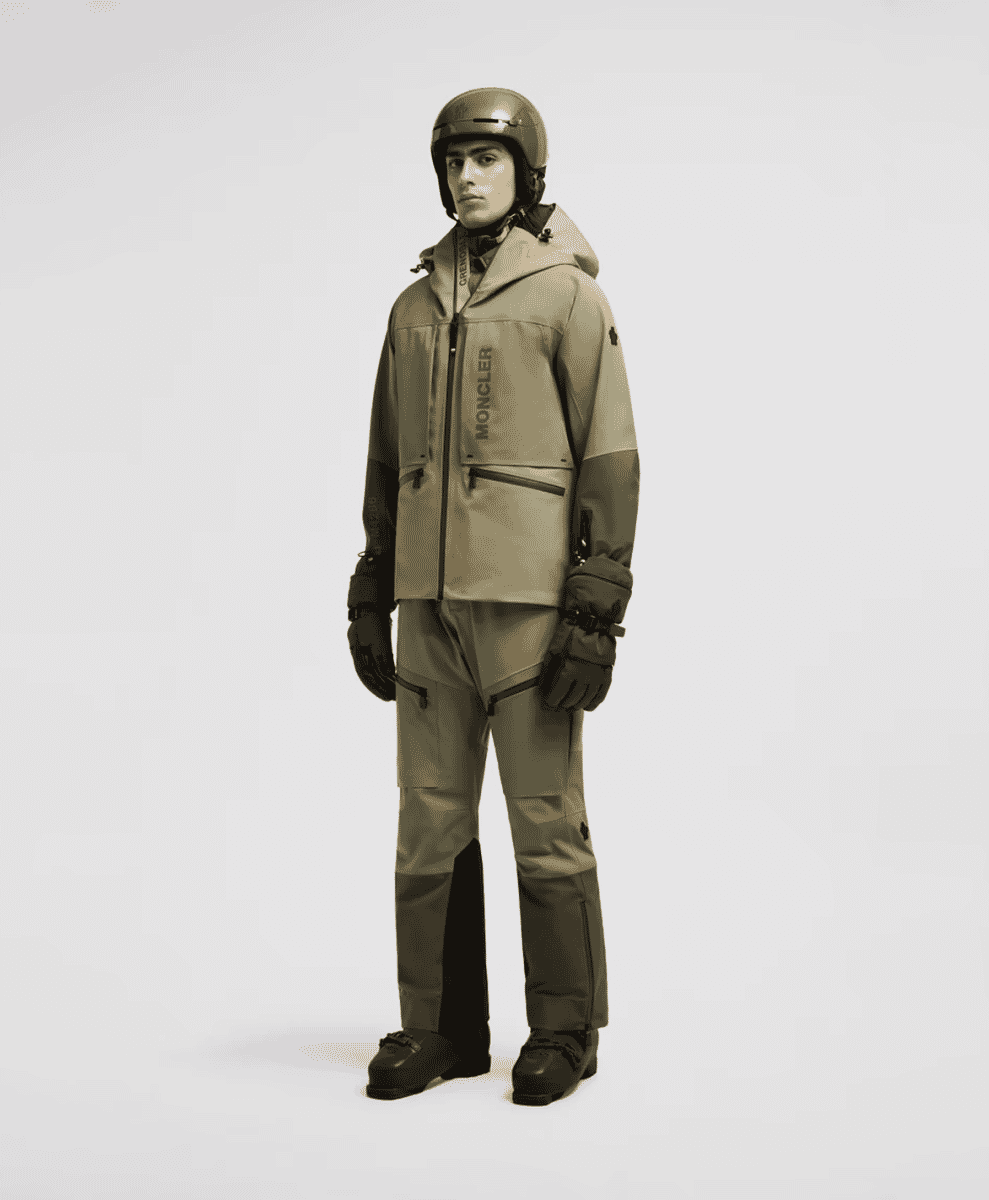 A male model in a tailored monochromatic beige and dark gray ski suit.