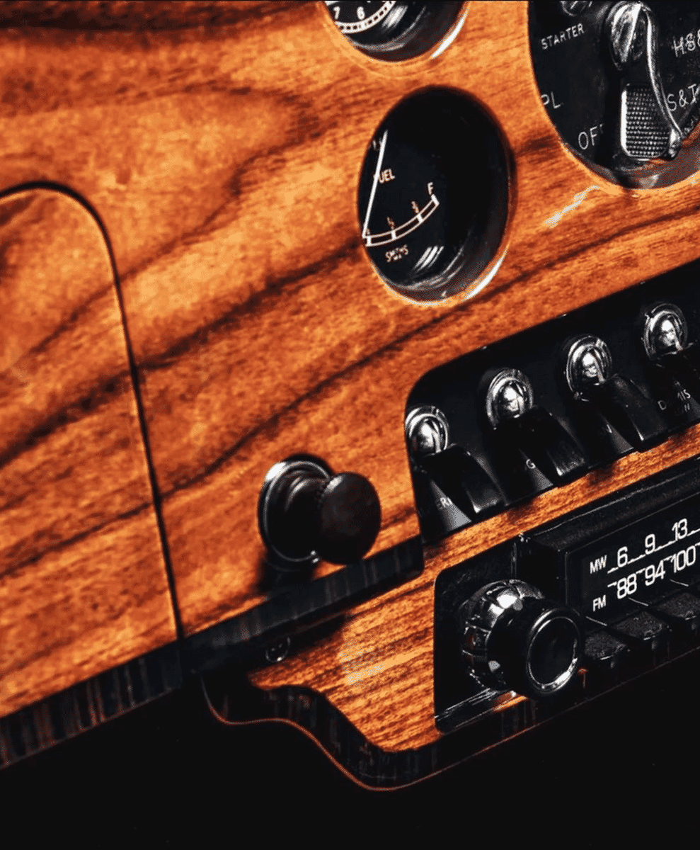 Close-up of a vintage car dashboard with wood grain and analog gauges.