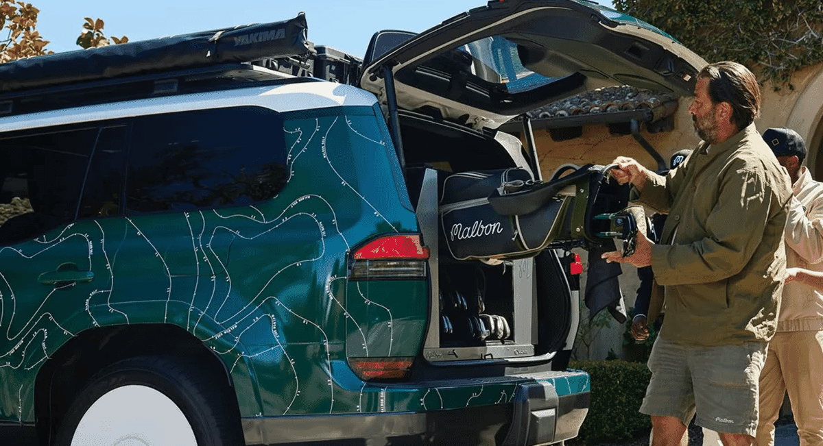 A man in khaki apparel loading a green and white Malbon golf bag into the trunk of a Lexus SUV.