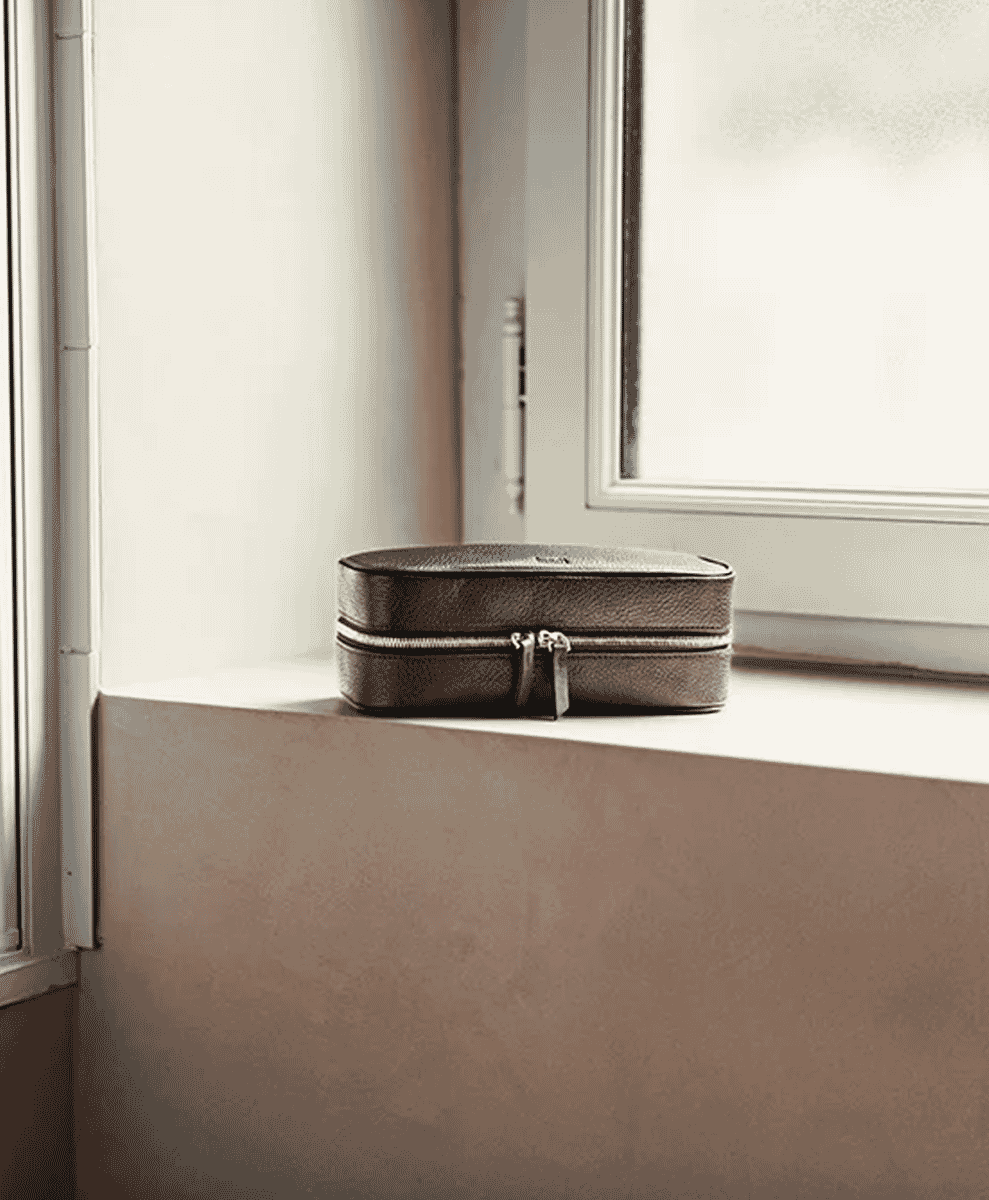 Chestnut full-grain leather toiletry bag on a sunlit windowsill