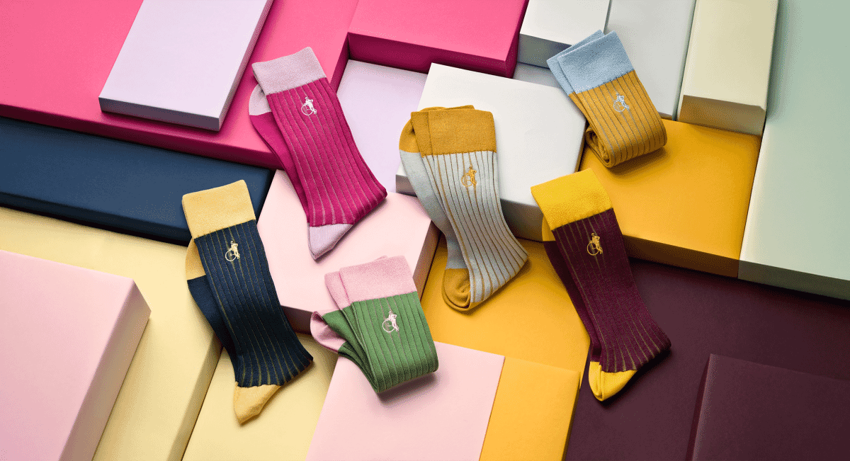 Colorful ribbed socks with brand logos displayed on pastel and bold geometric boxes.