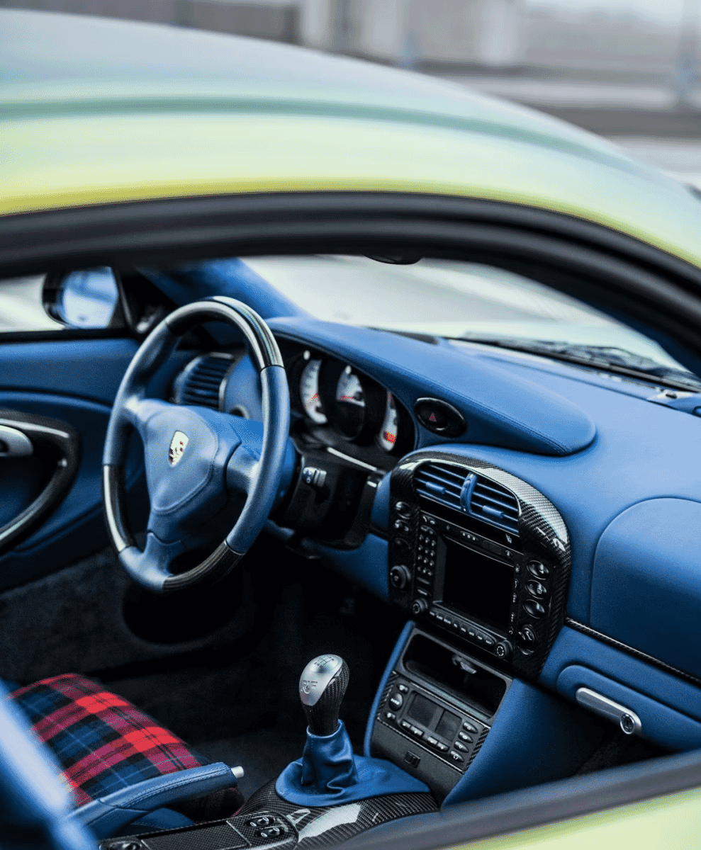 Interior of a customized Porsche with blue leather and plaid-patterned seat covers.
