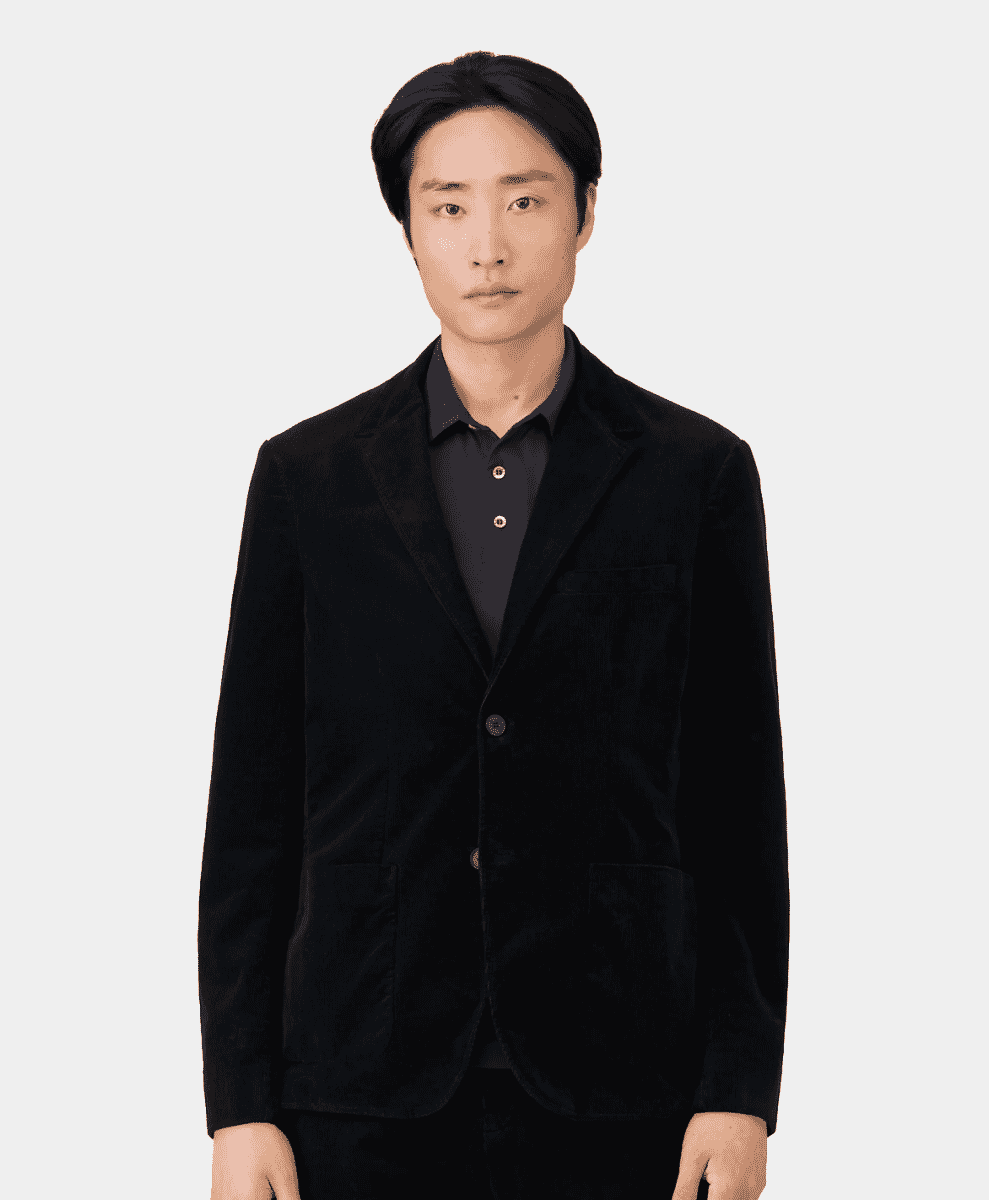 A man wearing a black corduroy blazer over a polo shirt.