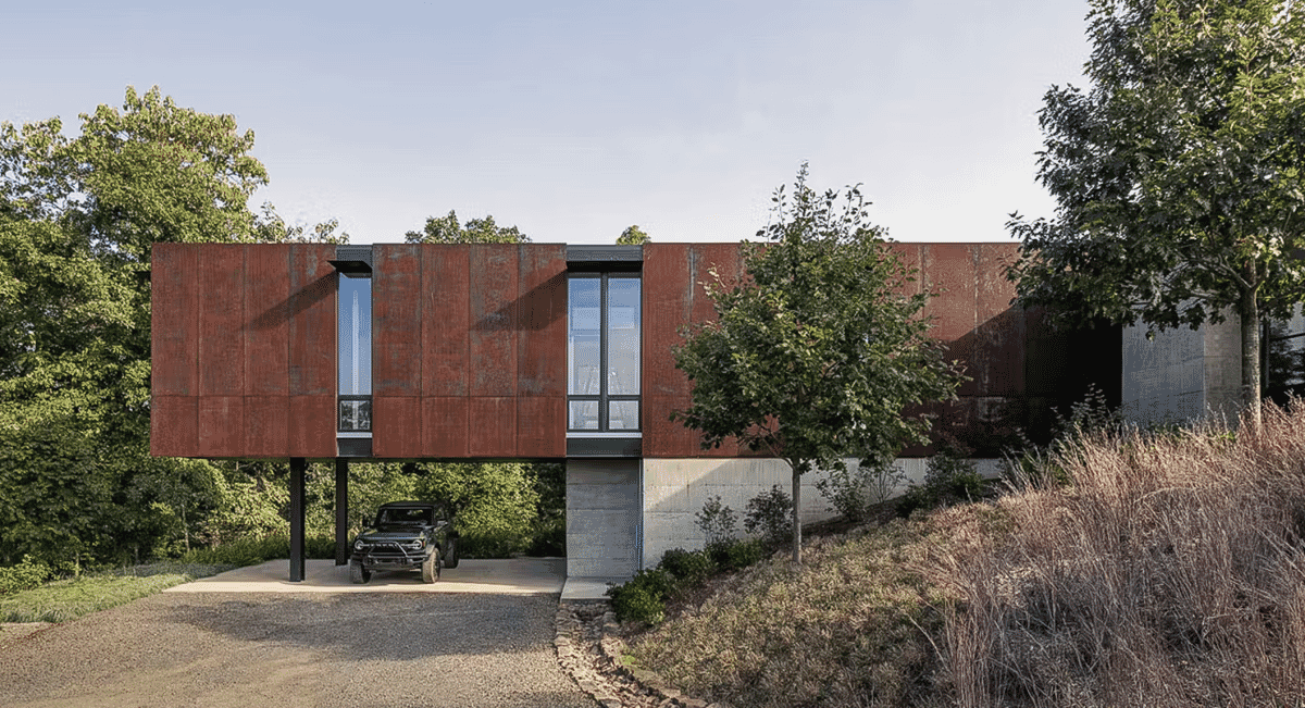 Exterior view of a modern house featuring rust-colored Corten steel panels and large glass windows.