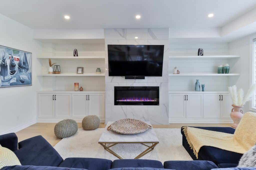 White built-in shelves flanking a fireplace, filled with books and decorative objects.