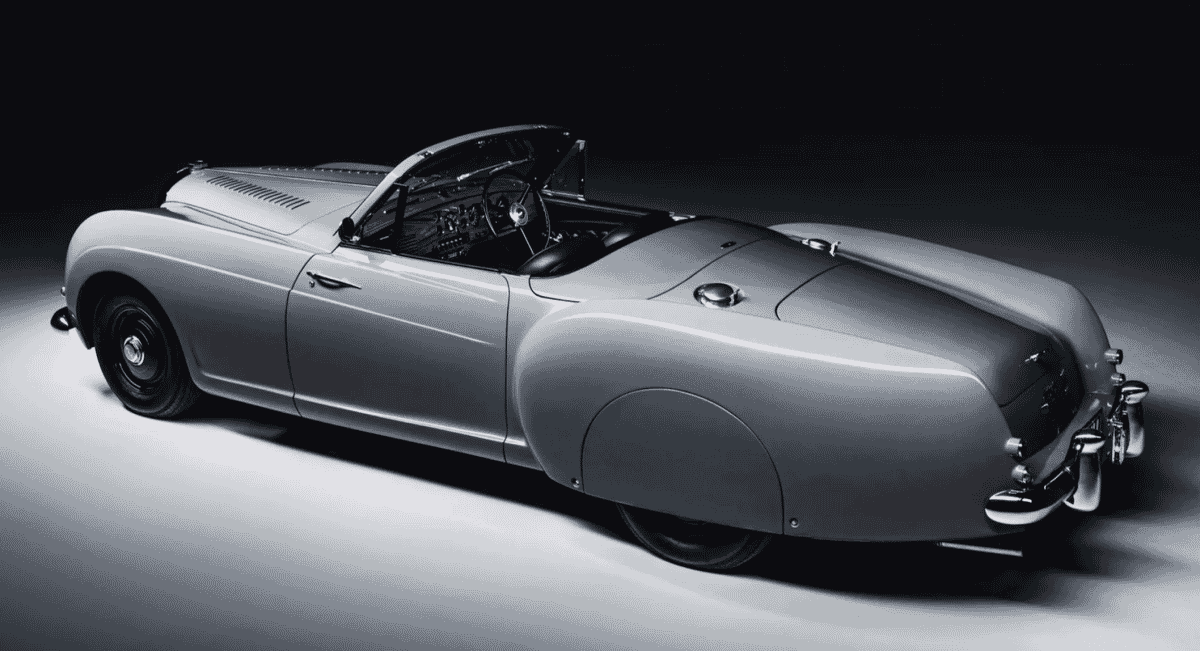 Sleek 1953 Bentley R-Type Continental convertible in monochrome against a dark background.