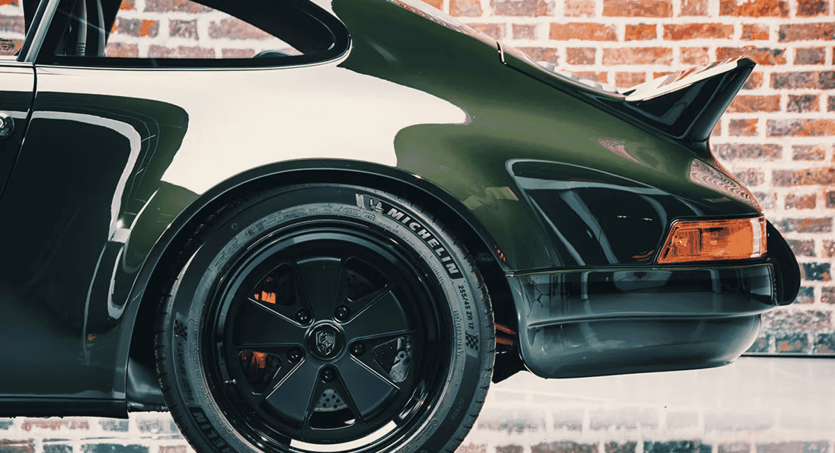 Side profile of a green Porsche 911 featuring high-performance Michelin tires and black wheels.