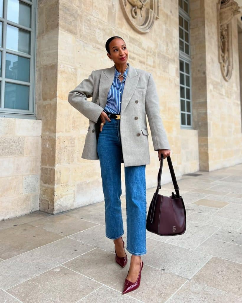 A woman in wide-leg denim, a blue striped shirt, and burgundy heels posing outdoors.