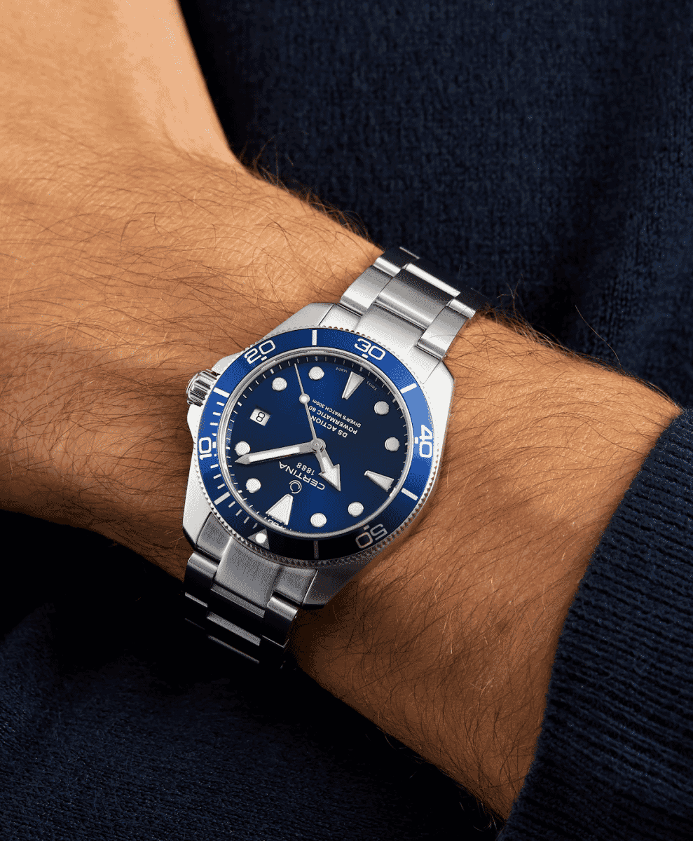 Wrist shot of a Certina watch with a blue dial paired with a navy blue sweater.