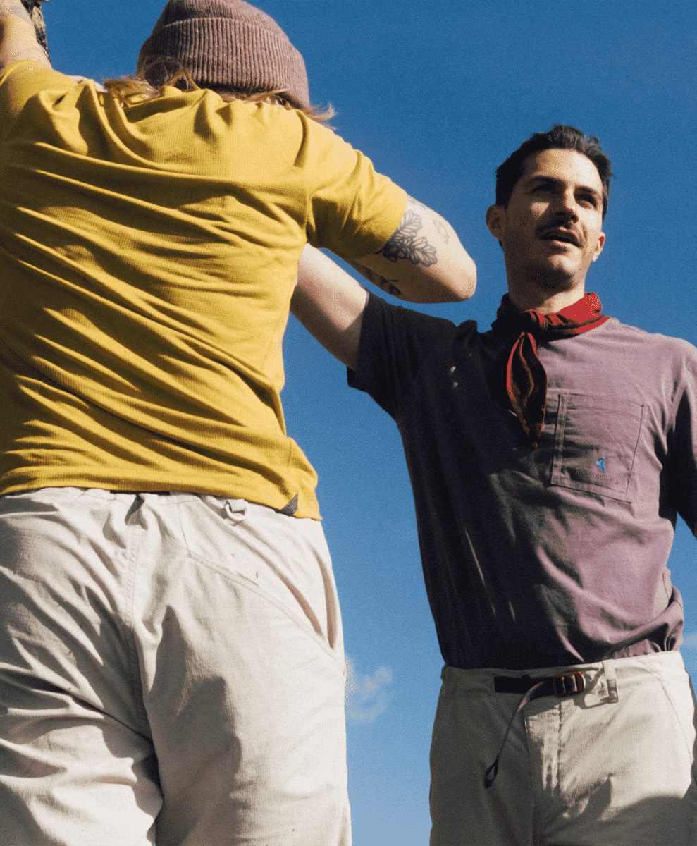 Two people in casual outdoor shirts posing against a clear blue sky.