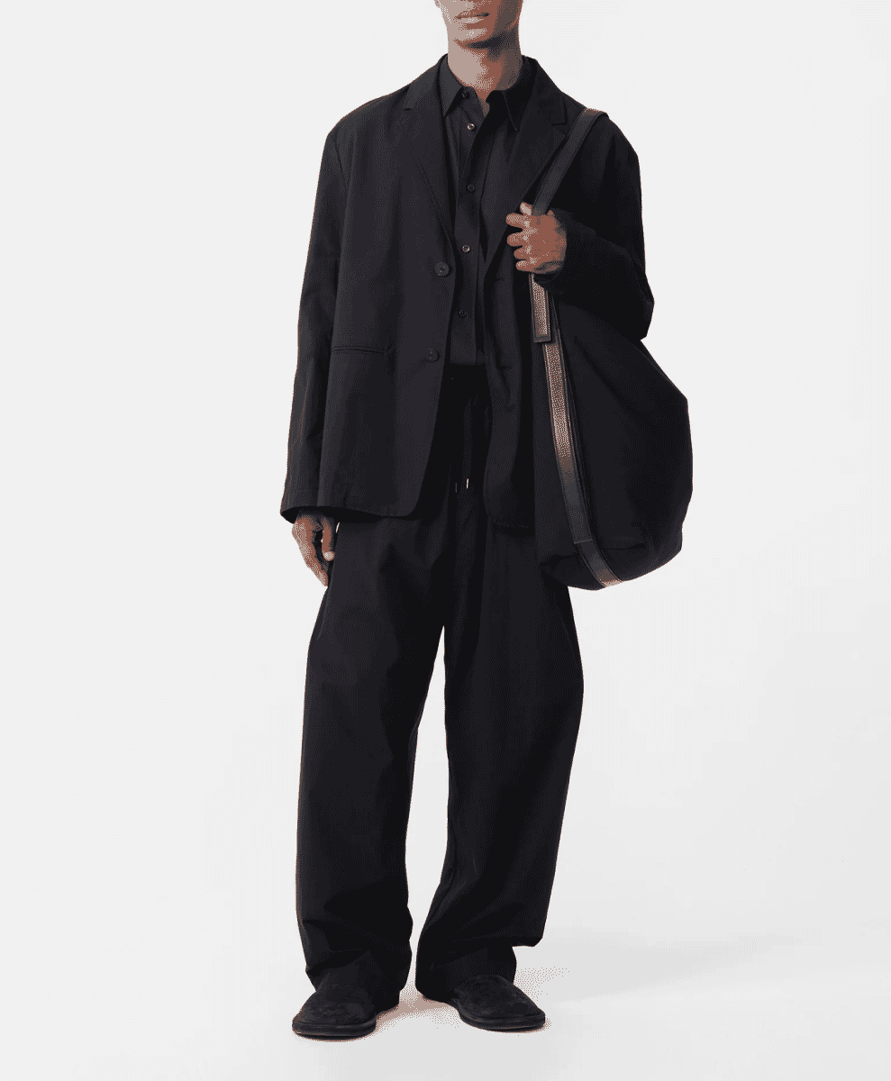 Model in an all-black oversized ensemble with a blazer and tote bag.
