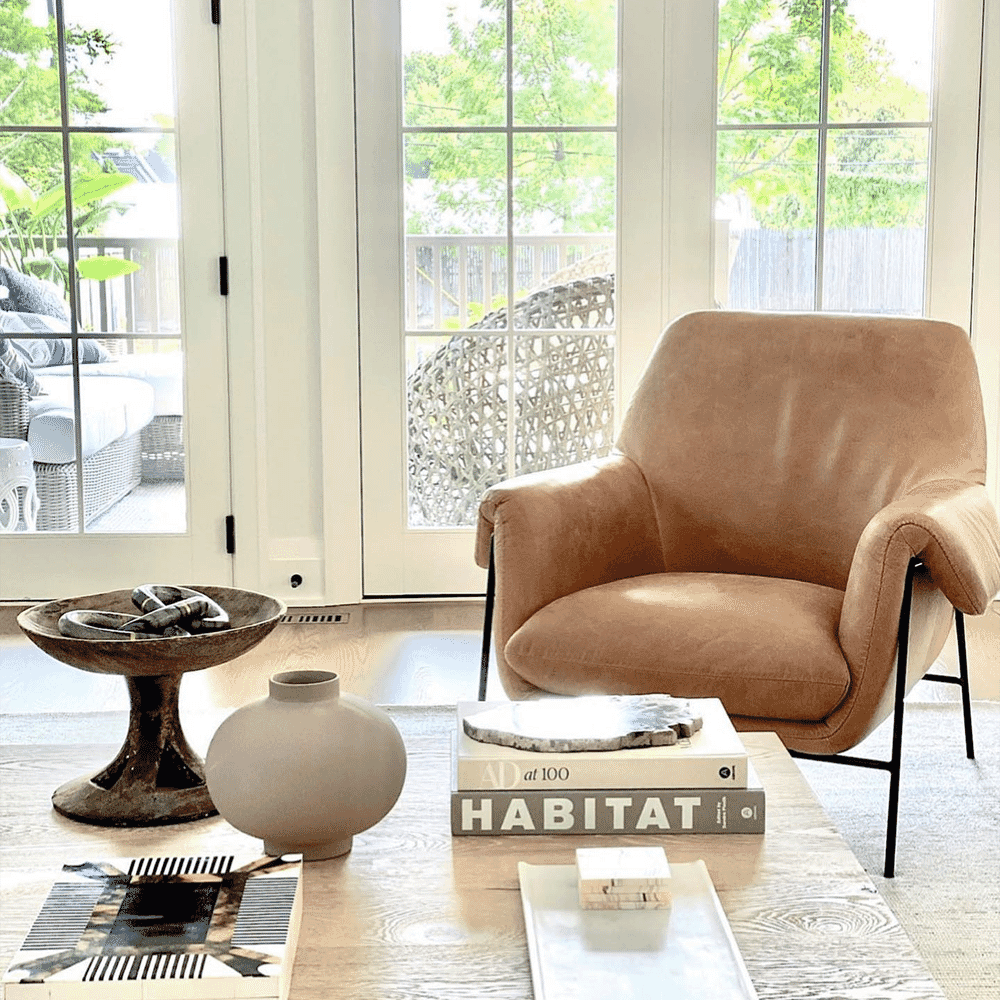 A tan leather armchair in a sunlit living room with a wooden coffee table.