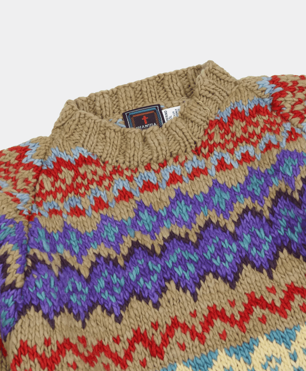 Macro shot of a chunky multi-colored knit sweater with a visible CHAMULA brand tag.