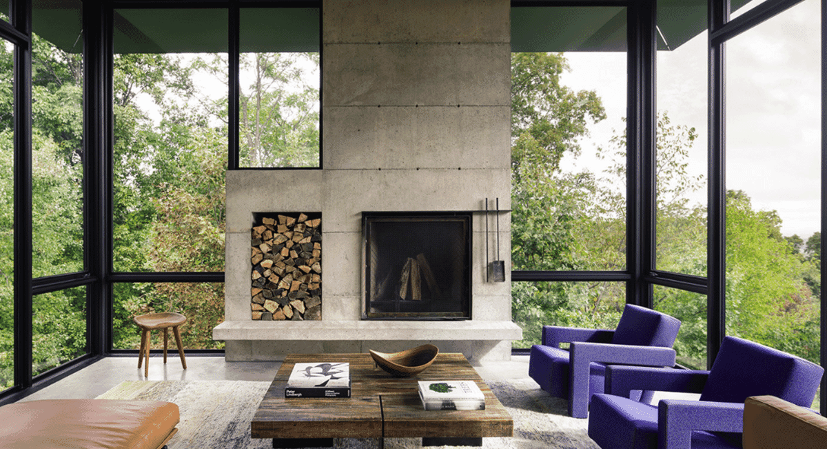 Modern living room interior with a large concrete fireplace and vibrant purple velvet armchairs.