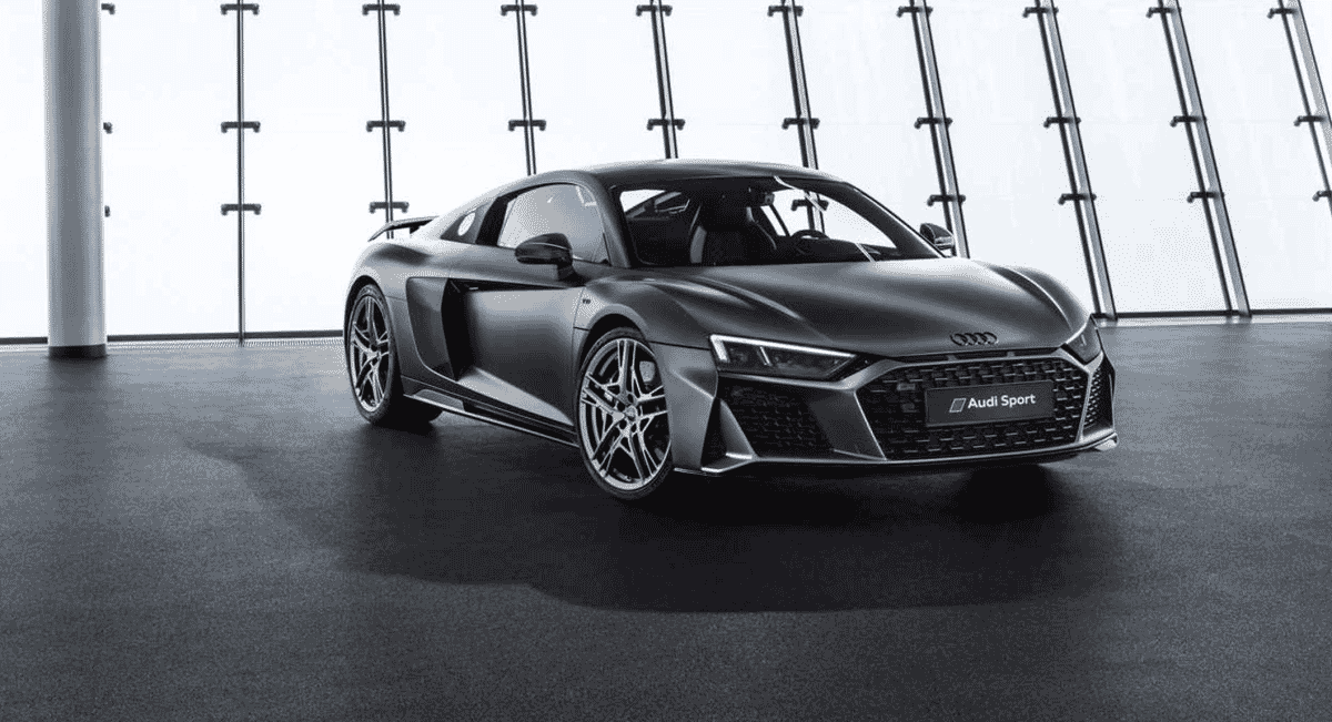 A matte gray Audi R8 displayed in a clean, modern glass showroom.