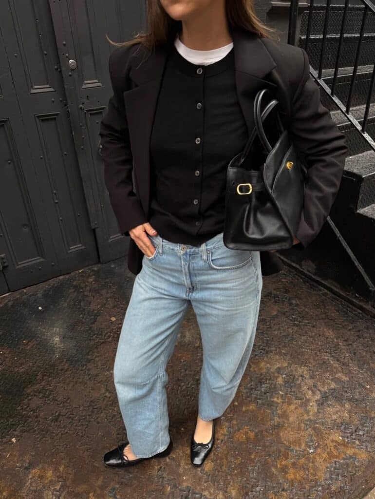 Woman wearing dark wash barrel leg jeans with a tucked-in top and sleek footwear