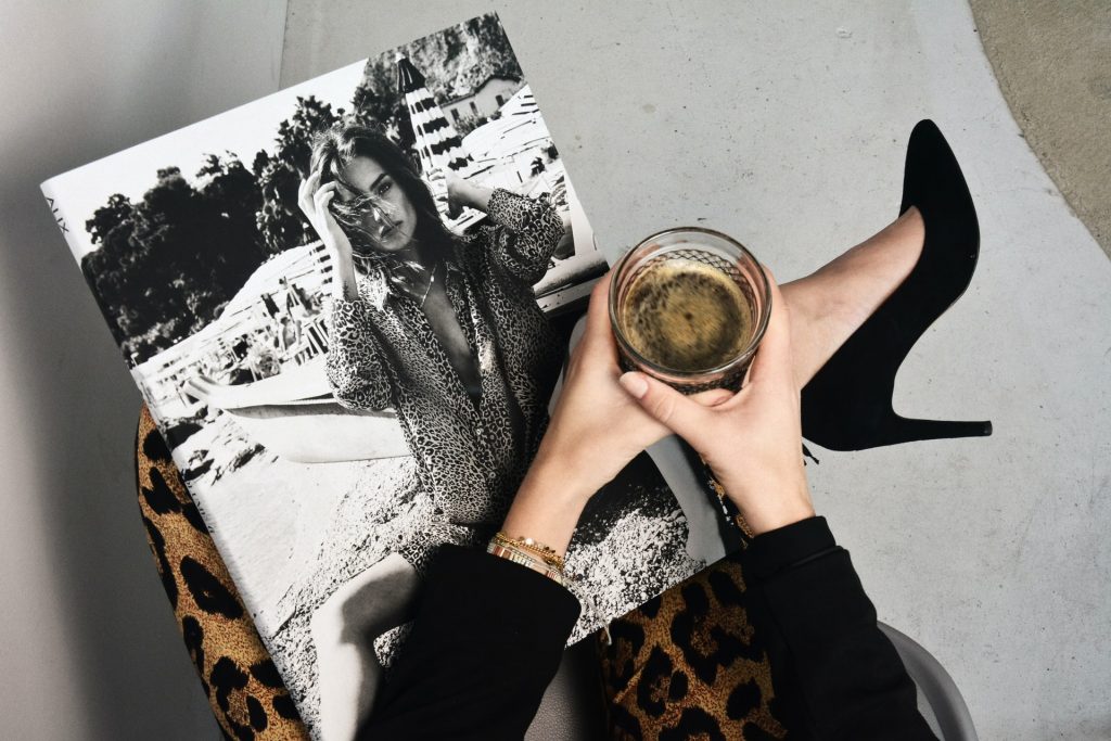 Overhead view of leopard-print pants and high heels next to a coffee cup and fashion magazine.