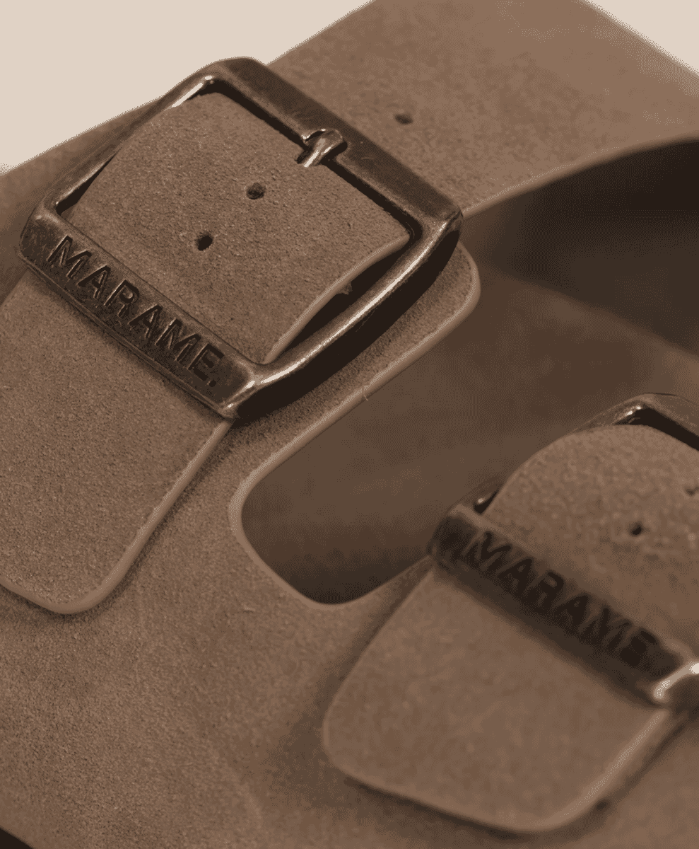 Detailed close-up of metallic buckles on suede sandals featuring the MARAME logo
