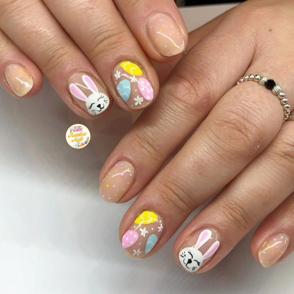 Intricate bunny and colorful egg nail art on a nude base.