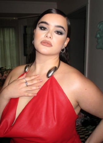 A woman in a bold red one-shoulder dress with metallic shoulder accents.