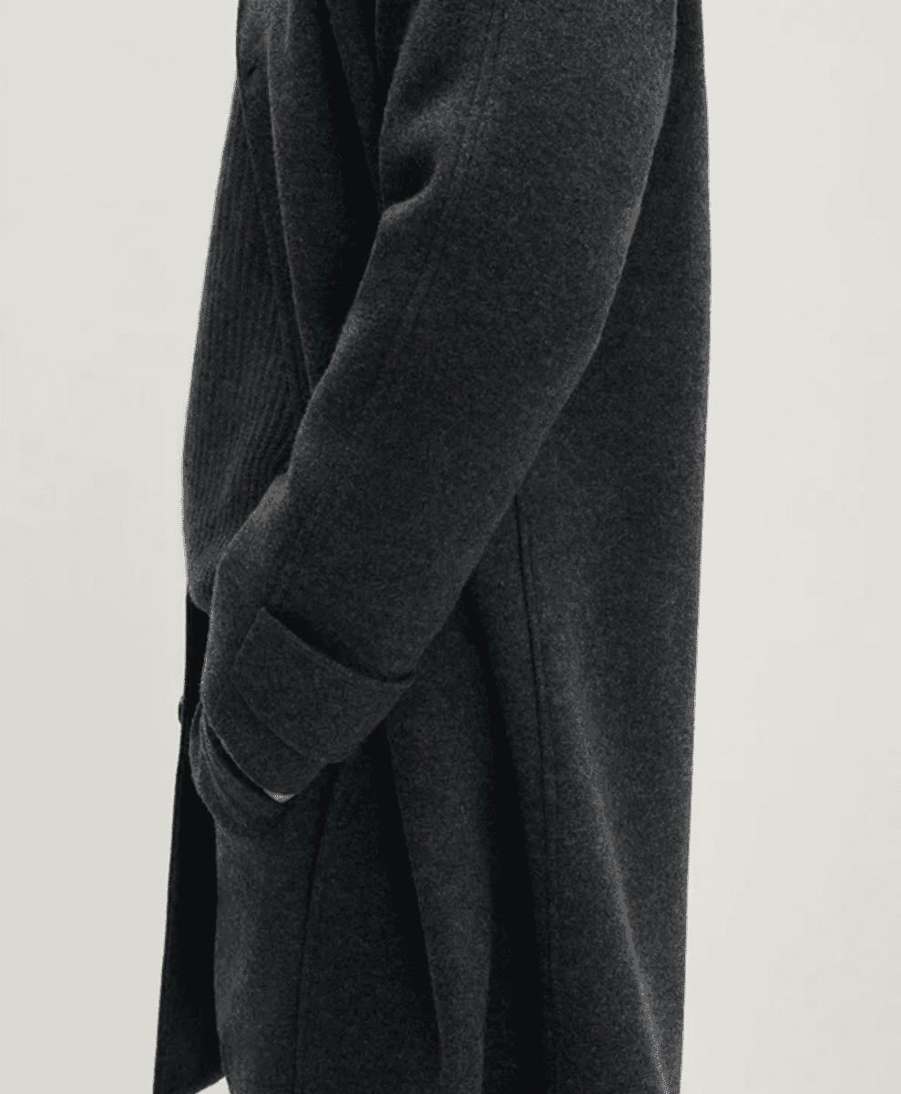 Close-up detail of a dark gray textured wool coat showing fabric grain.