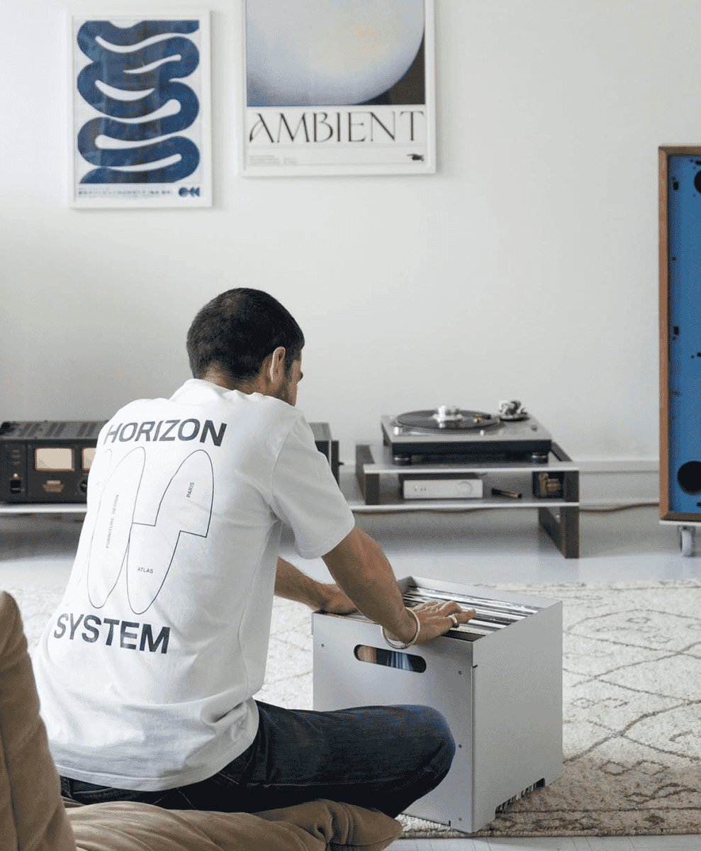 A man in a Horizon System graphic t-shirt browsing vinyl records in a modern room.