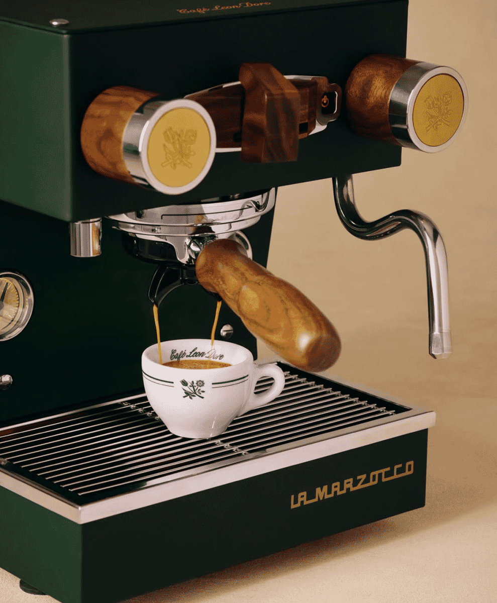 Close-up of espresso pouring from a La Marzocco machine into a branded Café Leon Dore cup.