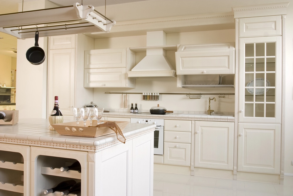 Close-up of a white luxury kitchen featuring an island, high-end faucet, and sophisticated cabinetry.