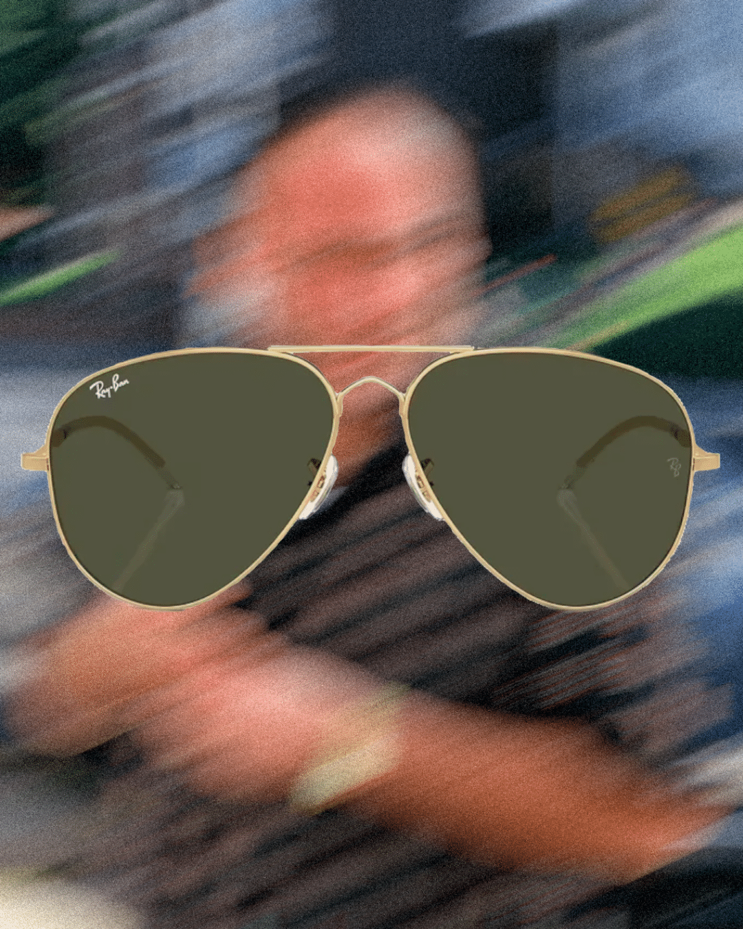 Man wearing gold-framed Ray-Ban aviator sunglasses with dark lenses and a striped shirt.