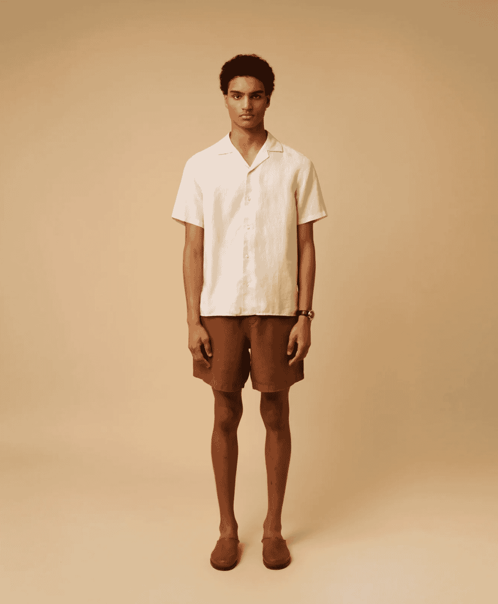 Man modeling a white short-sleeved linen camp collar shirt with brown shorts.