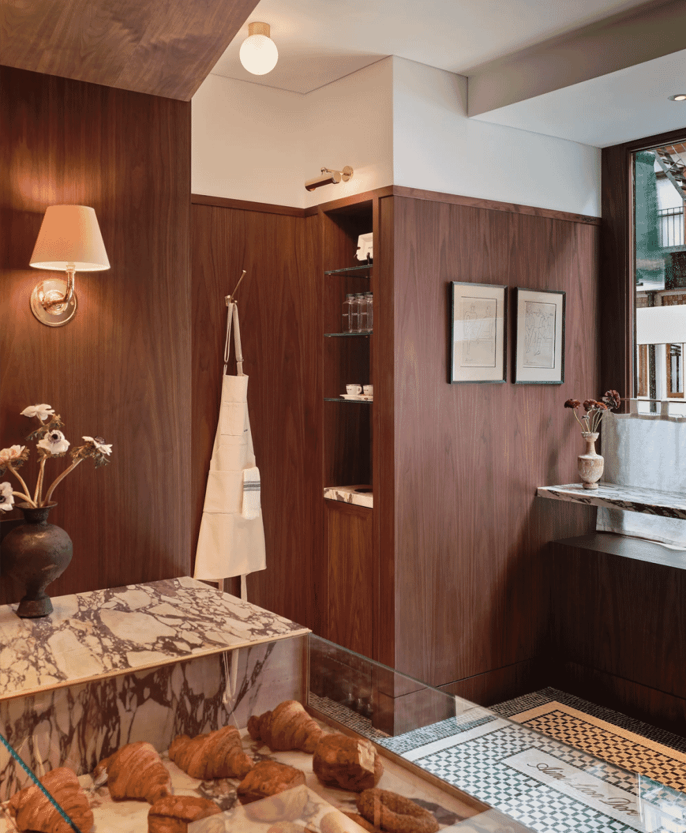 A blue-striped white apron hanging in a rustic bakery setting with wooden shelves.