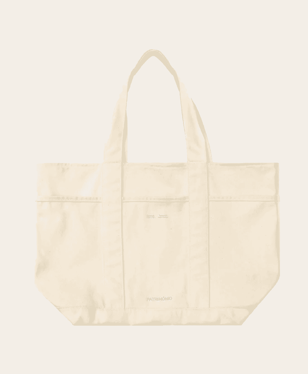 A cream-colored canvas tote bag with dual handles and front pockets.