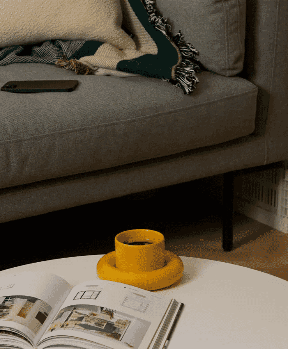 A yellow ceramic cup on a coffee table in a modern living room.
