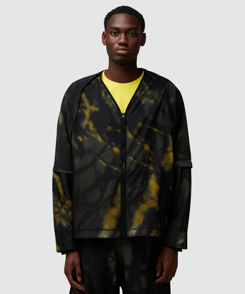 Studio shot of a model in a vibrant black and yellow tie-dye technical jacket.