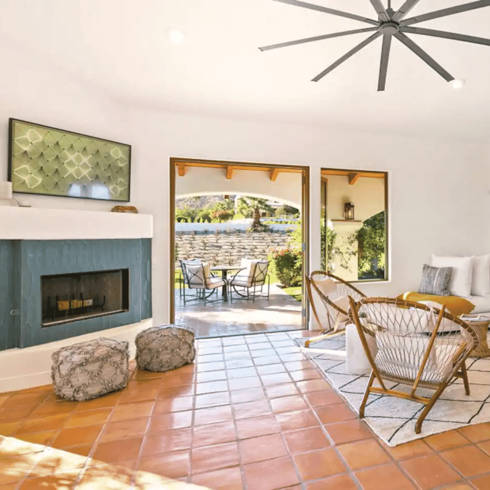 Sunlit living room with terracotta tiles, a blue fireplace, and sliding doors opening to a patio.