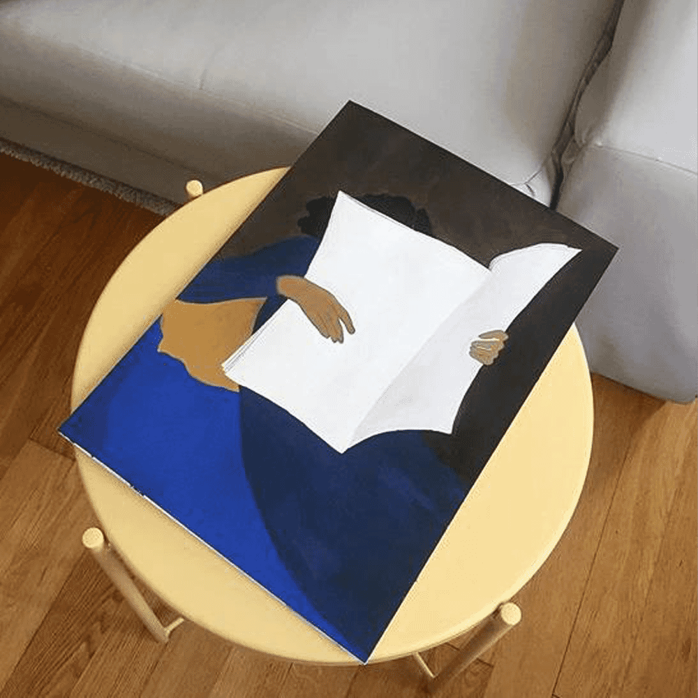 A modern painting of a person reading, displayed on a bright yellow stool in a contemporary living room.